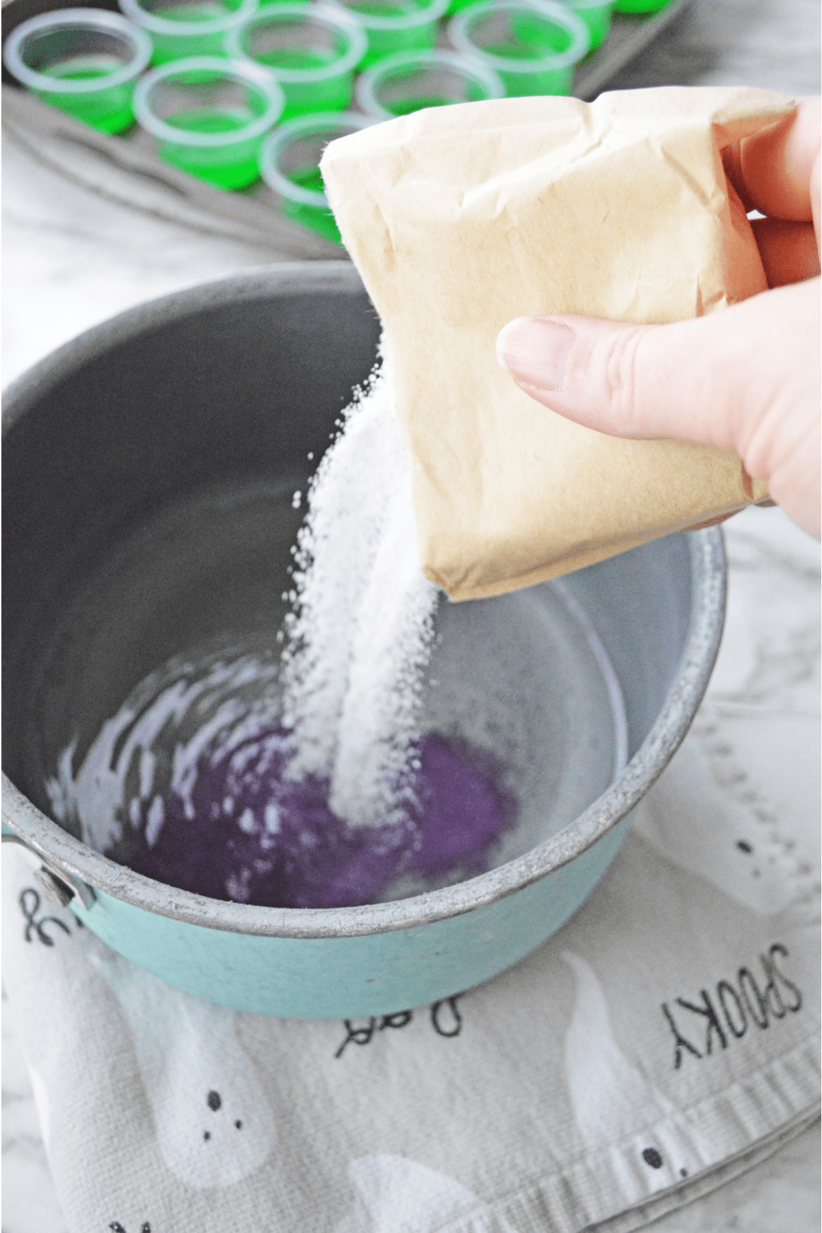 Pouring grape jello powder into saucepan with water