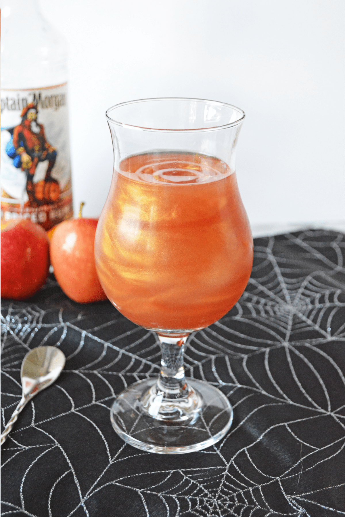 Poison apple cocktail with bottle of Captain Morgan spiced rum