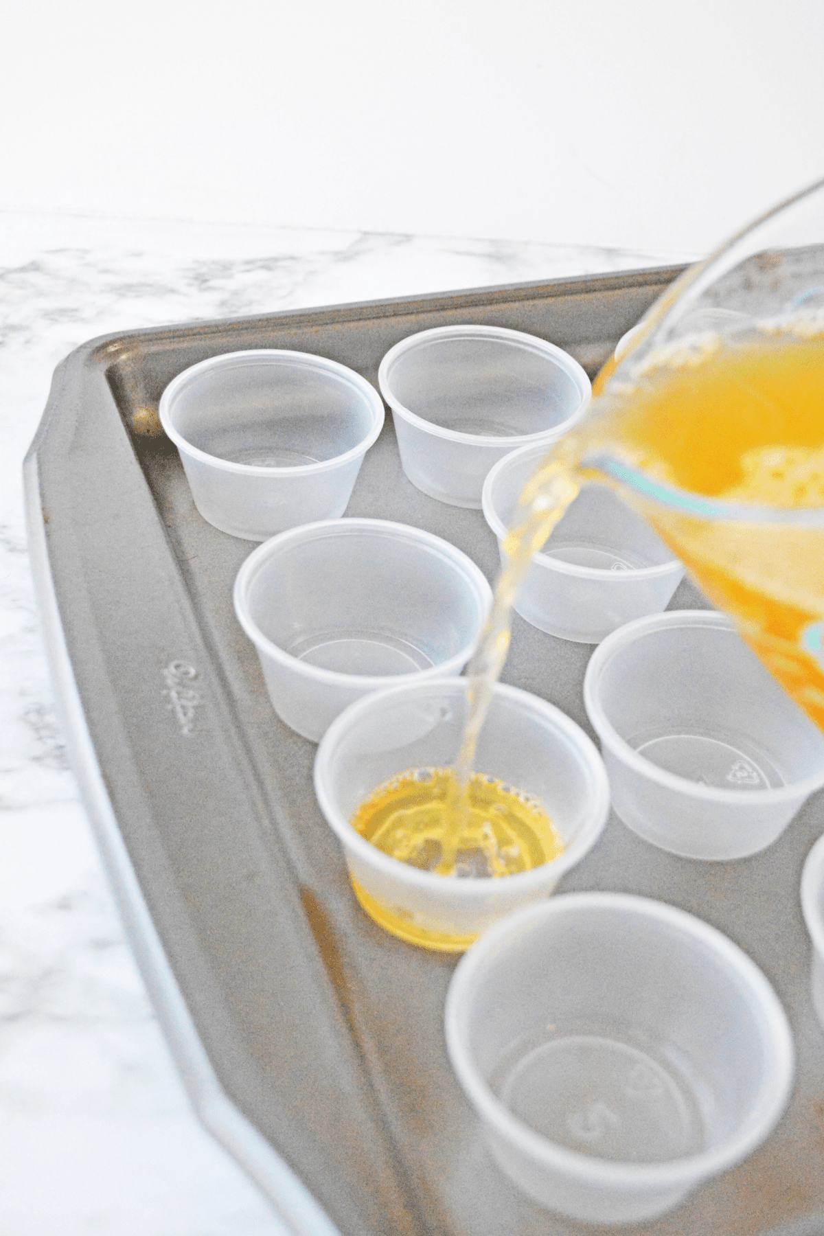 Pouring apple cider jello shot mixture into plastic cups