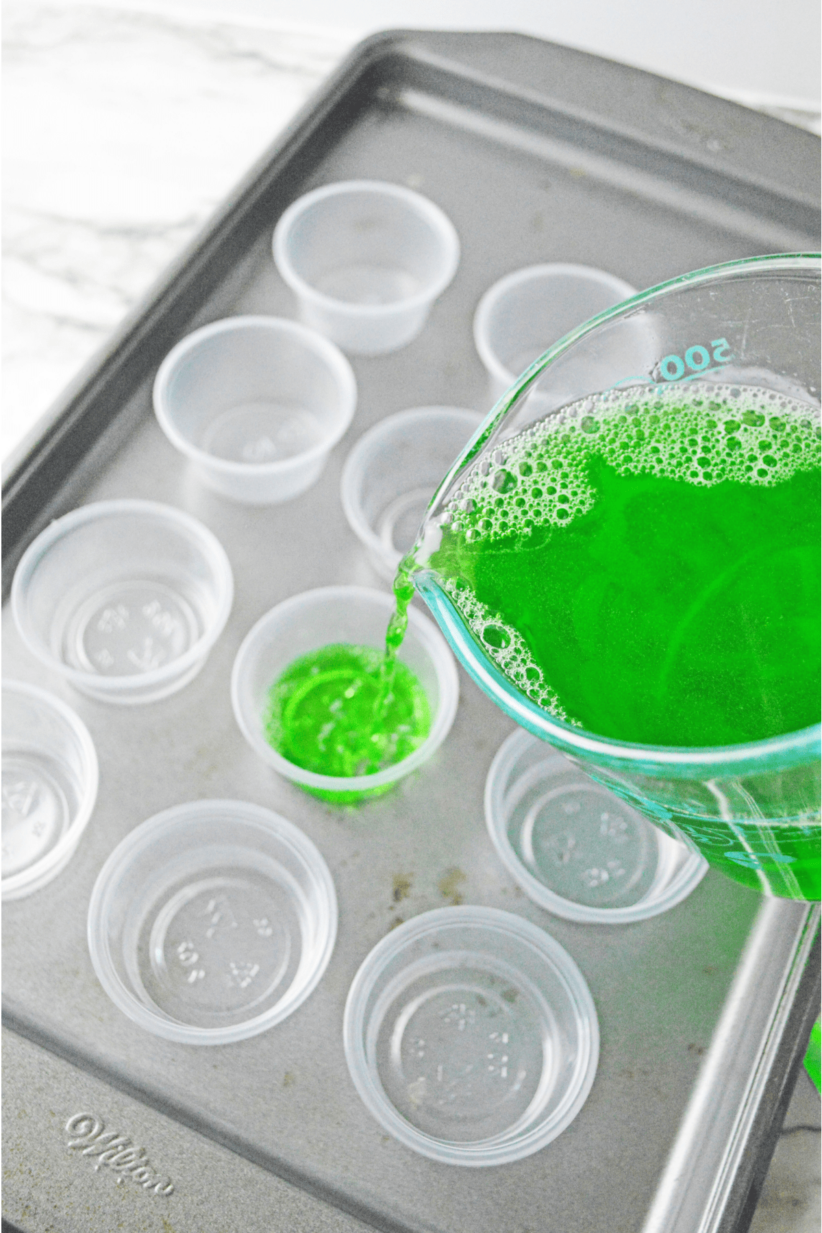 Pouring alcoholic Jello shot mix into plastic cups