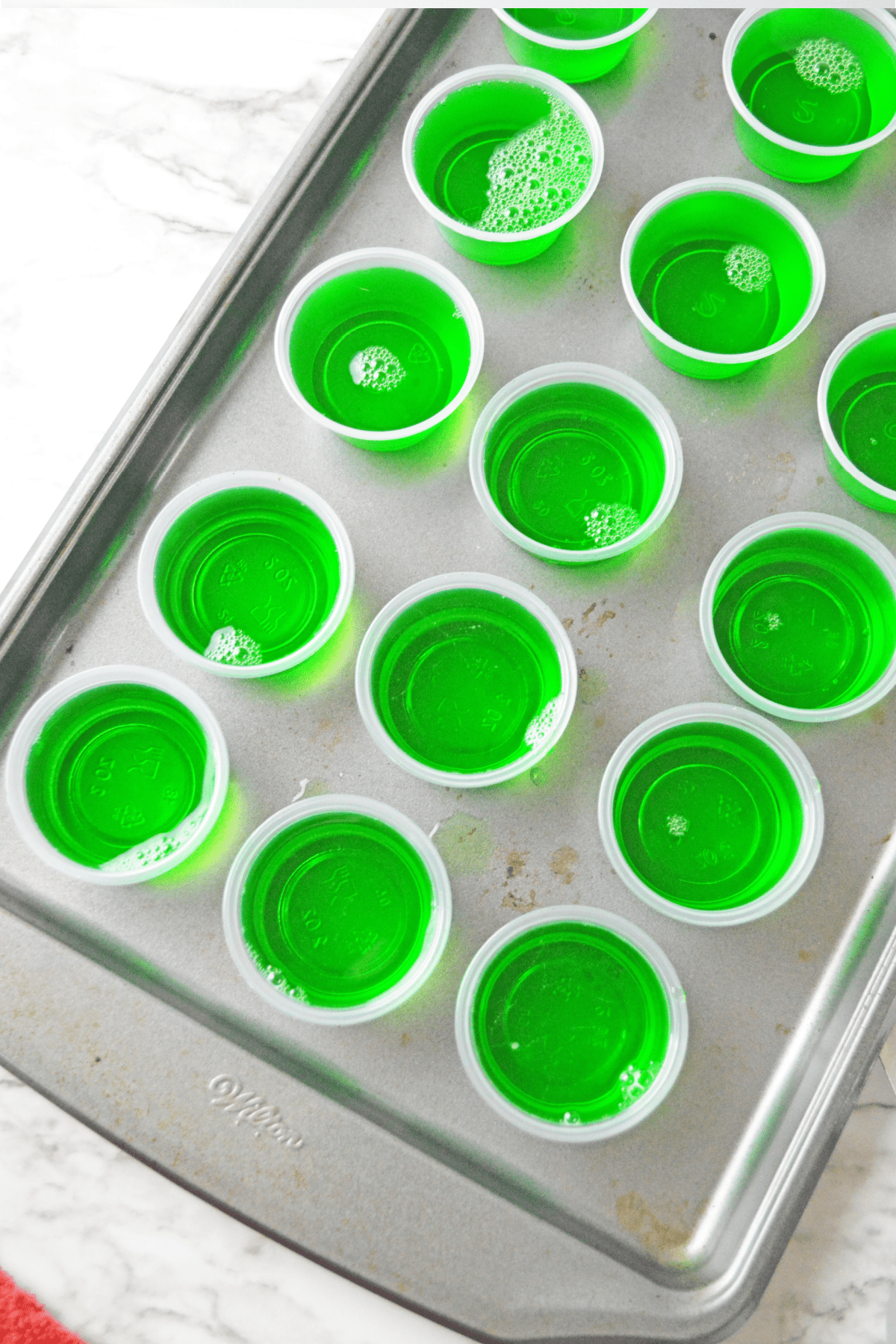 Plastic cups with green jello on cookie sheet