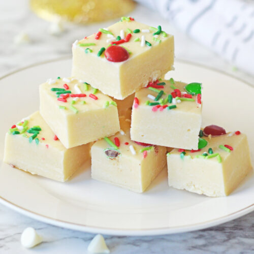 Christmas fudge on a white plate with sprinkles, perfect for holiday indulgence.