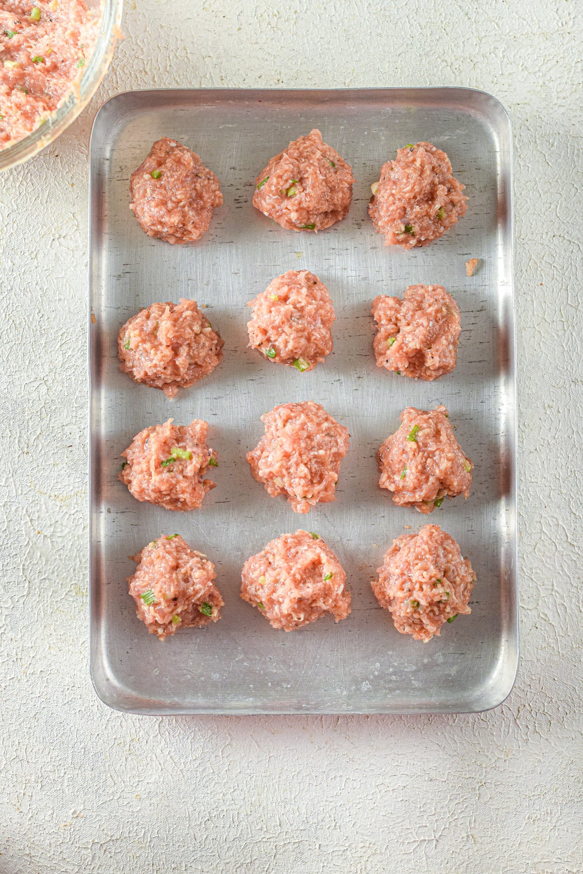 Raw meatballs on baking sheet