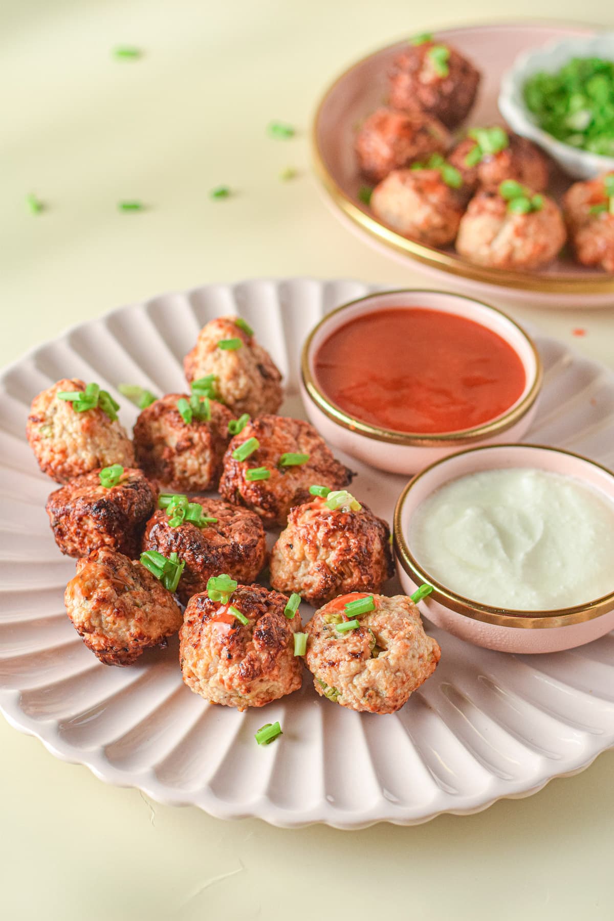 Buffalo Chicken Meatballs on topped with green onions on plate