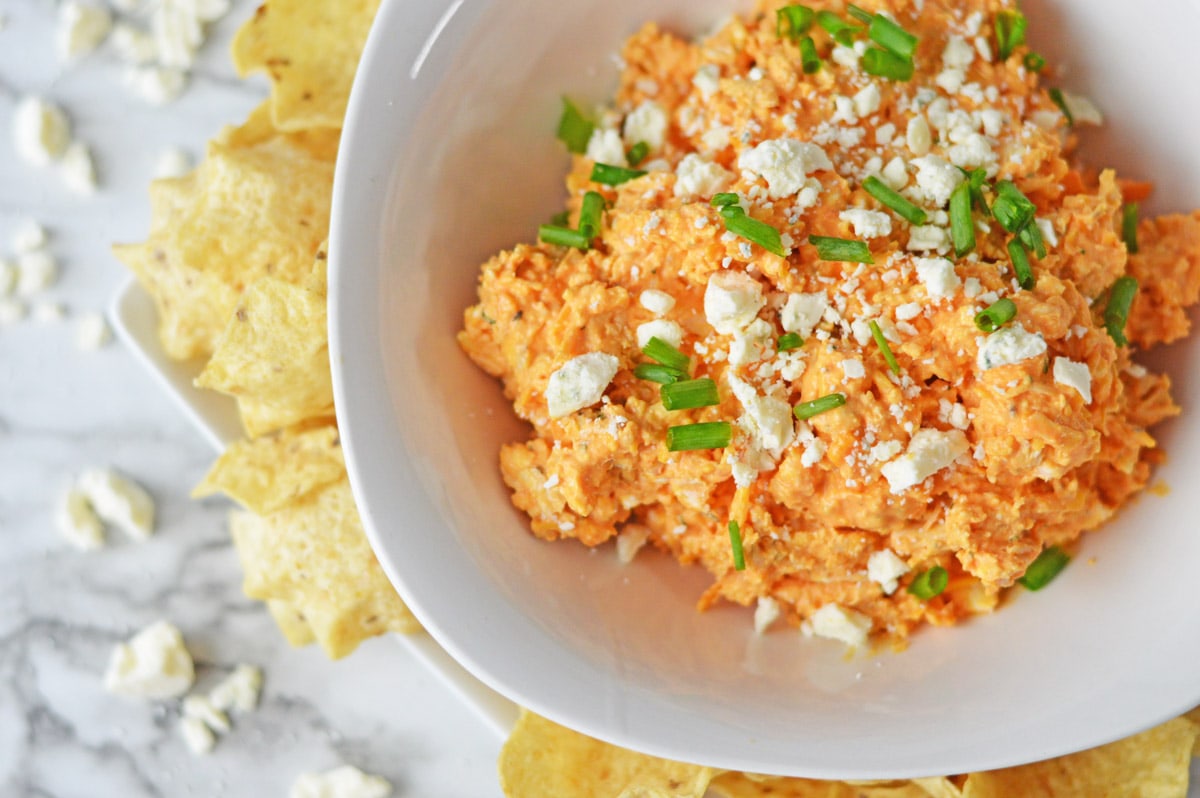 Cold Buffalo Chicken Dip in white bowl with chips around it