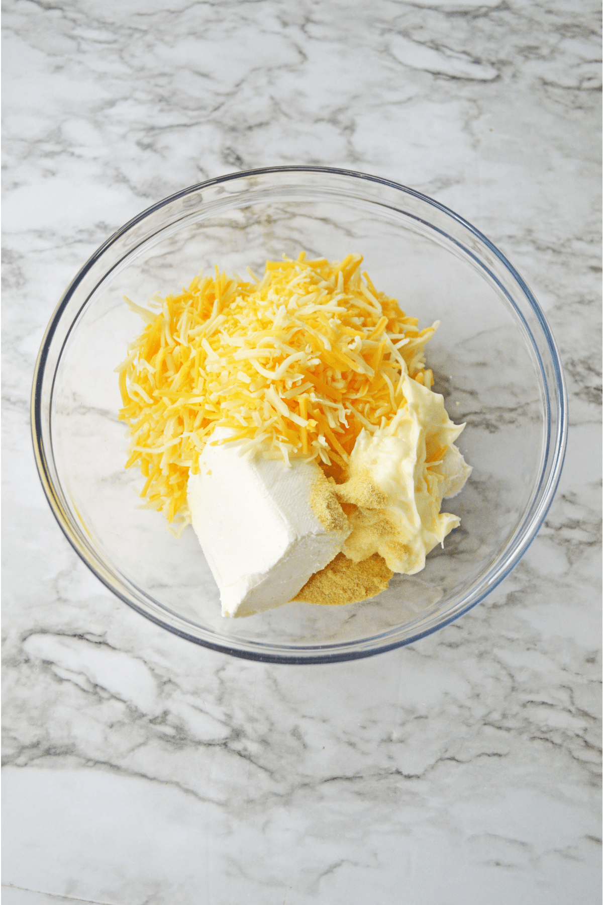 Cheddar, cream cheese and mayo in glass bowl