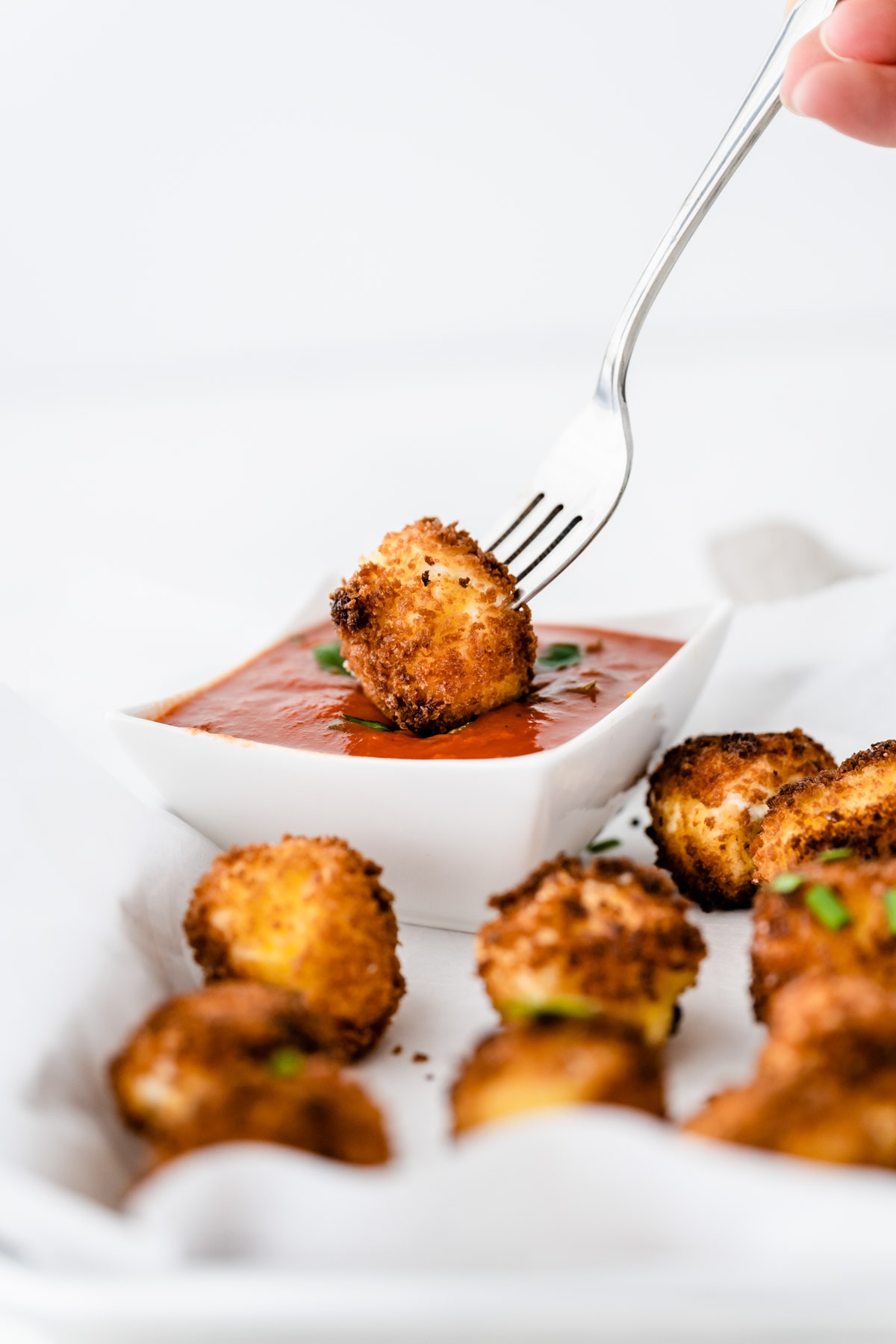 Fried goat cheese being dipped in marinara