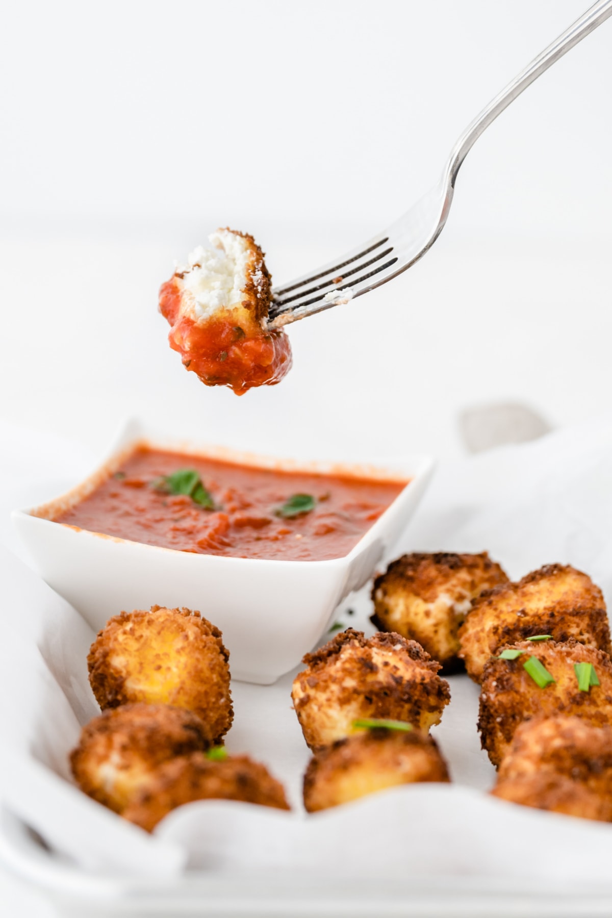 Fried goat cheese on fork dipped in sauce
