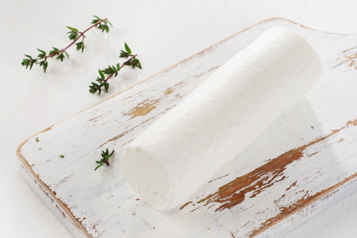 Goat cheese with fresh herbs on  white wooden table 