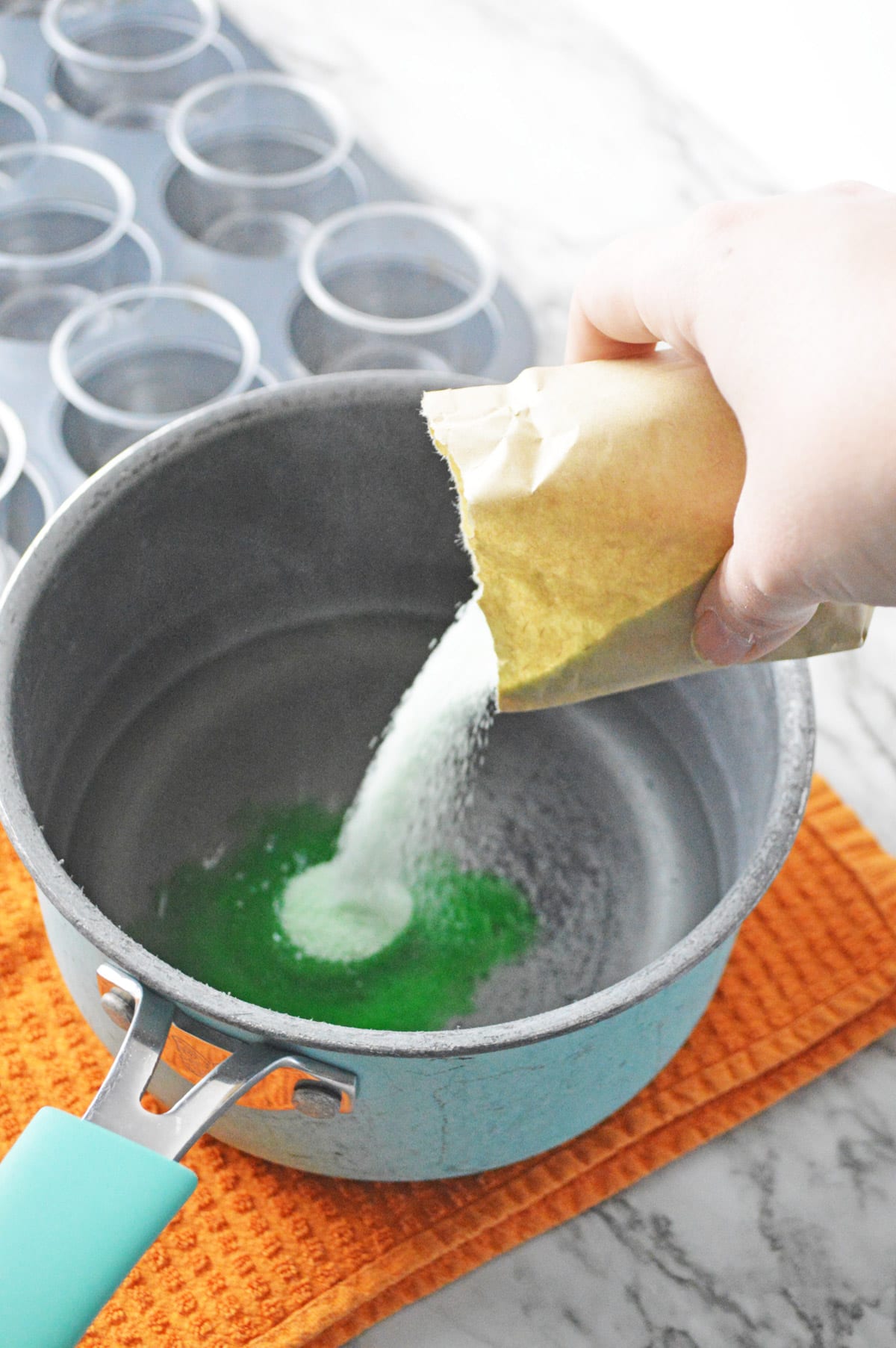 Pouring Jello mix into saucepan with water