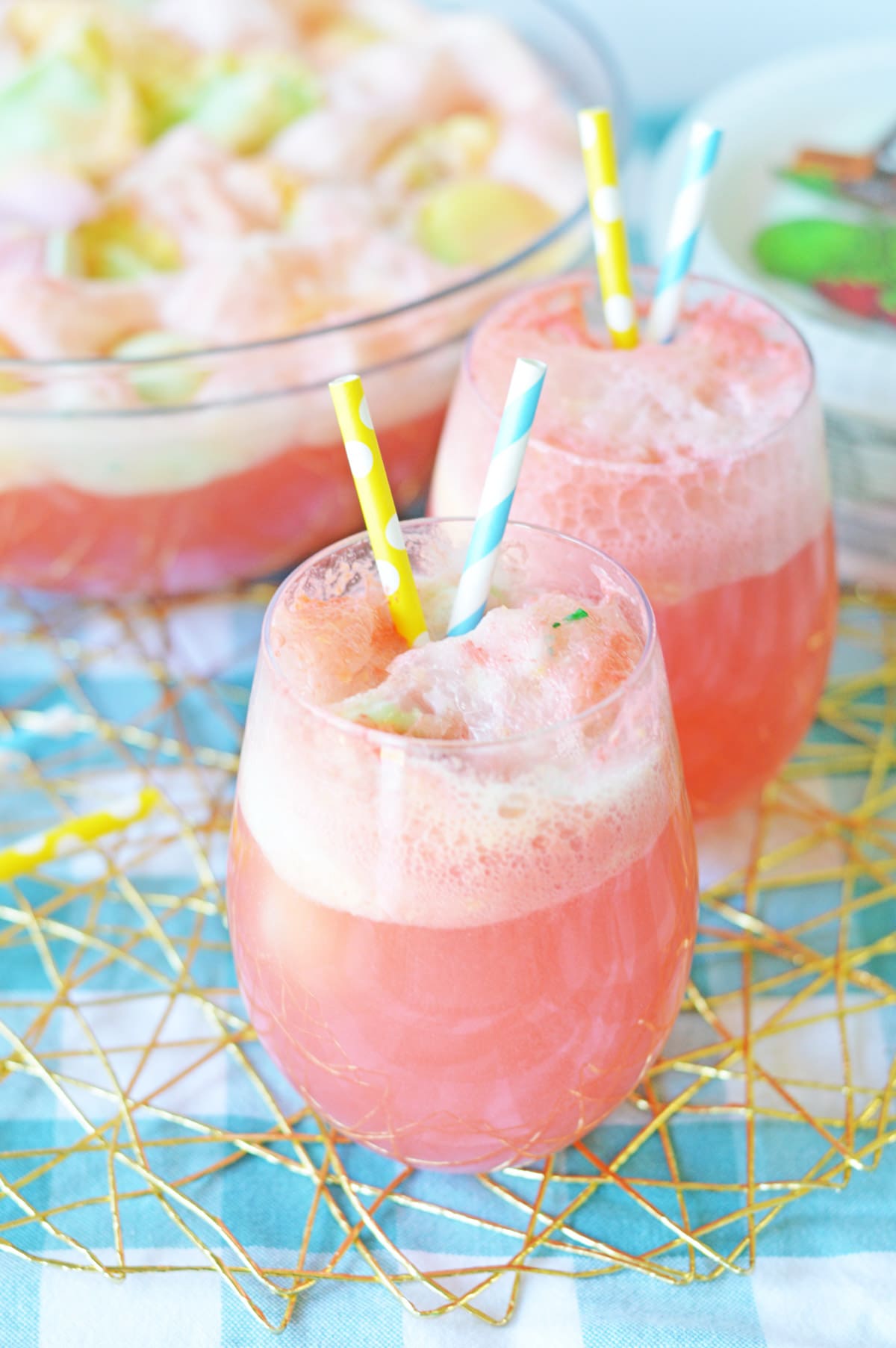 Two glasses of rainbow sherbet punch with straws