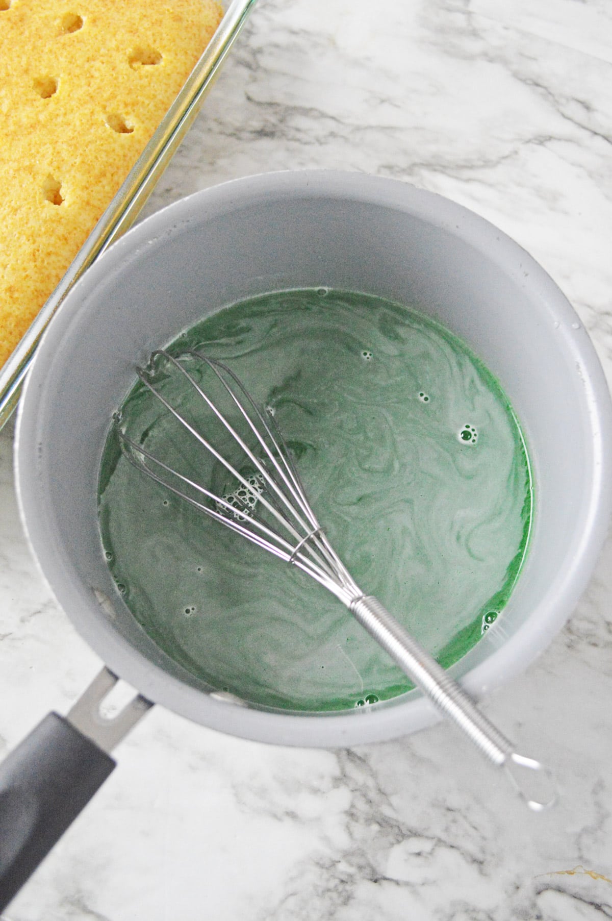 Green jello in saucepan with whisk