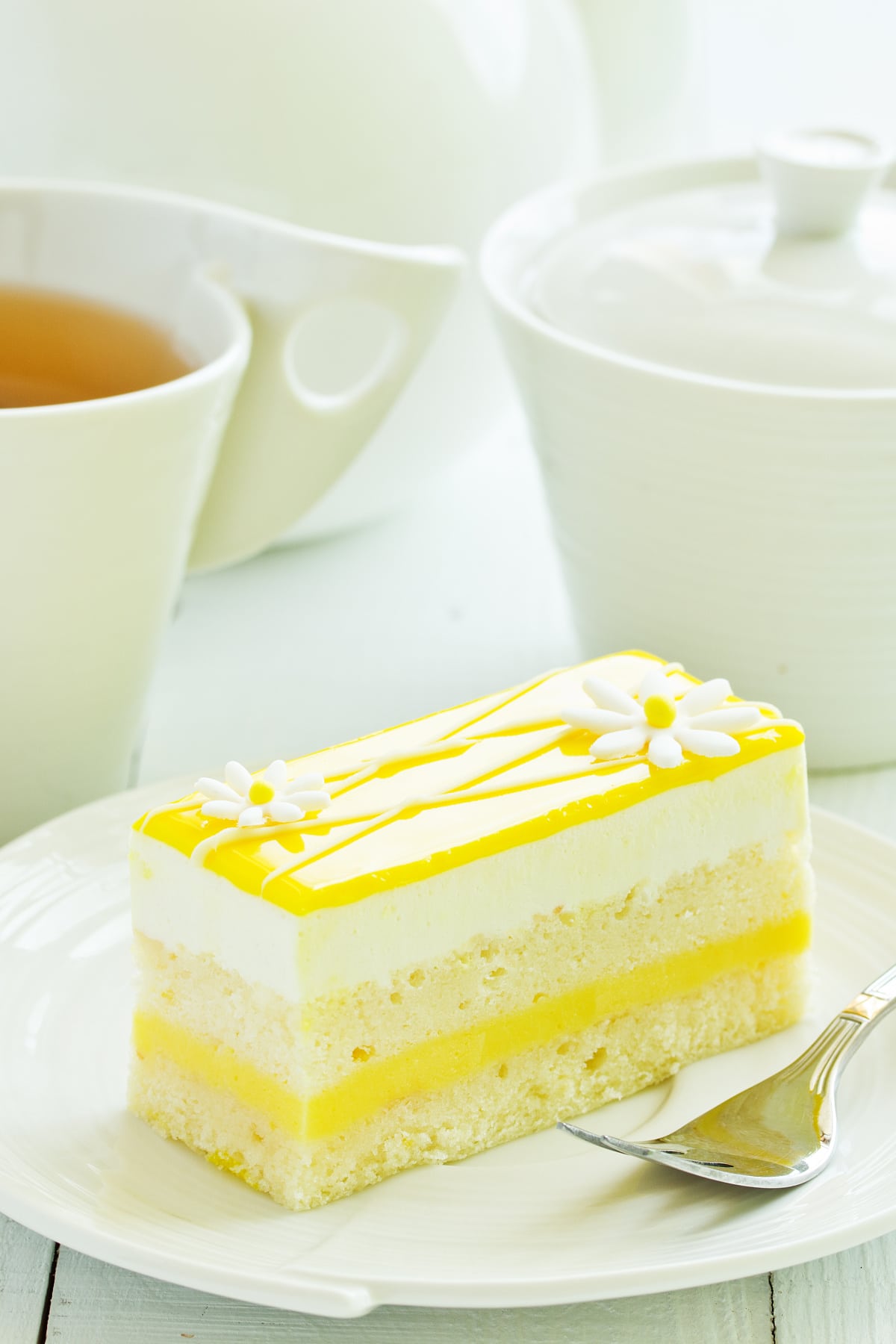 Lemon cake on white plate with tea in background
