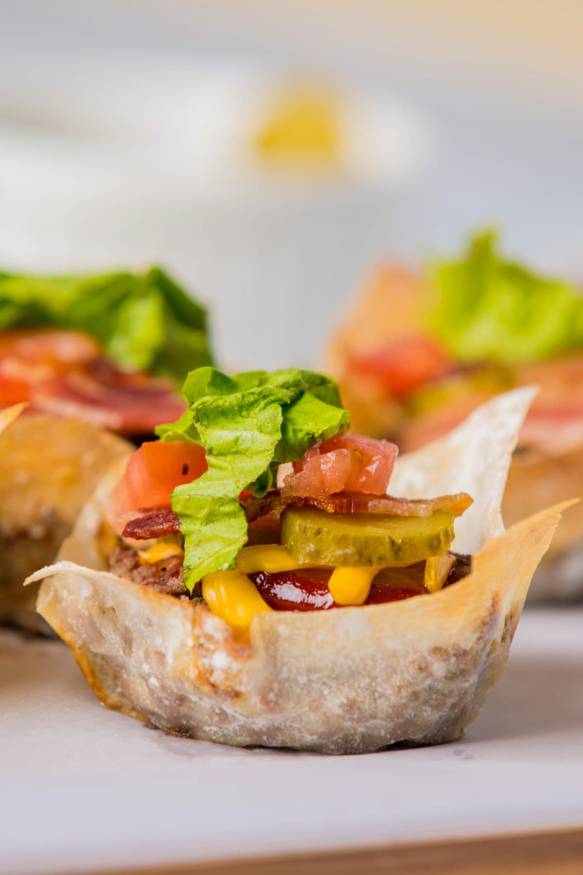 Finished cheeseburger cups garnished with bacon, lettuce, tomato and pickle