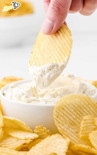 Hand dipping chip into white dip