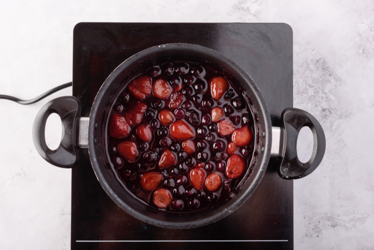 Strawberries and blueberries simmering in pan
