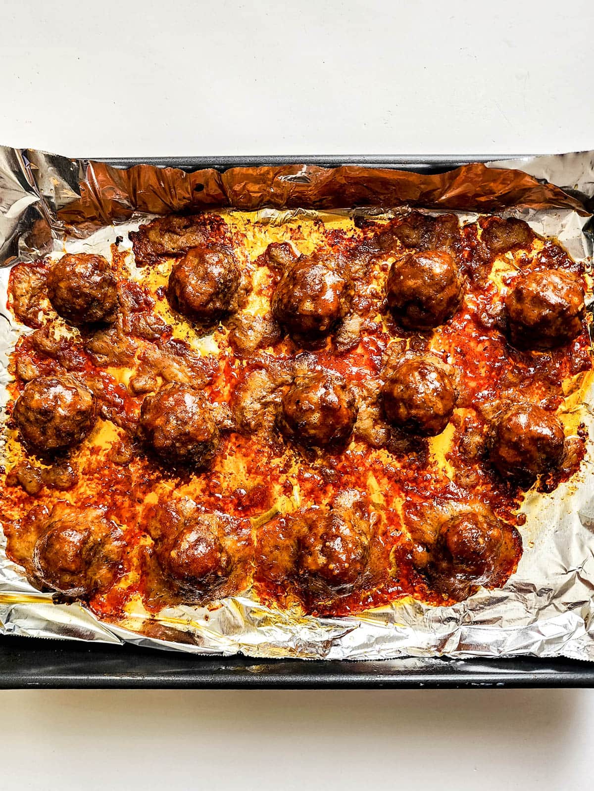 Cooked meatballs on foil covered baking sheet