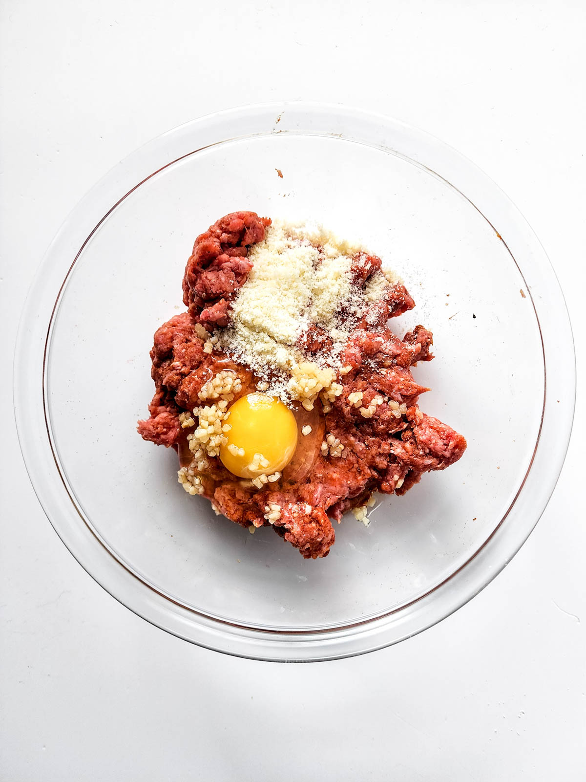 Ground beef with egg, garlic and cheese in glass bowl