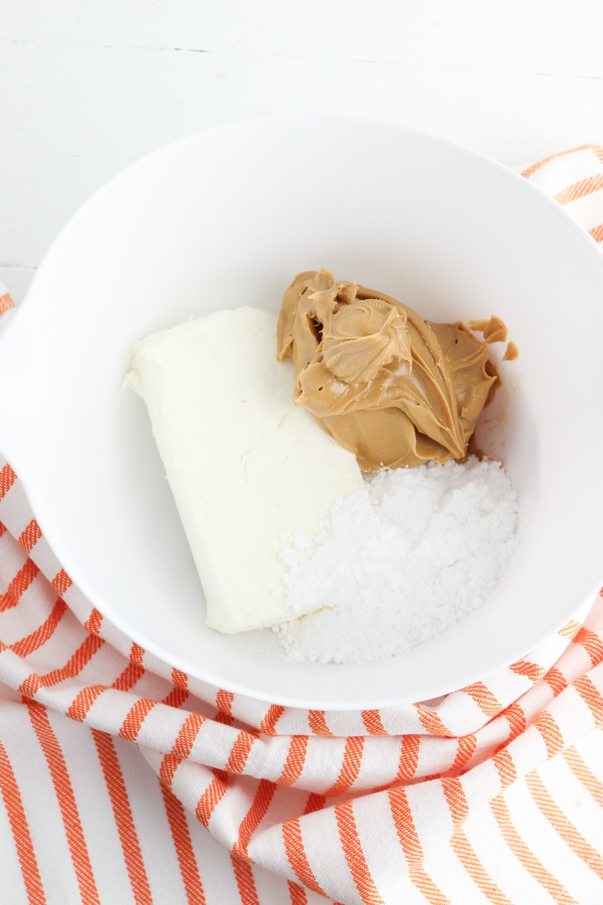 Peanut butter, sugar and cream cheese in white bowl