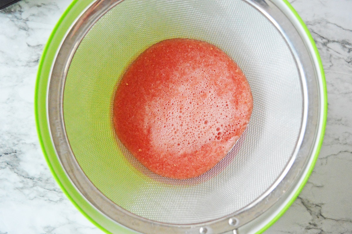 Filtering watermelon in strainer
