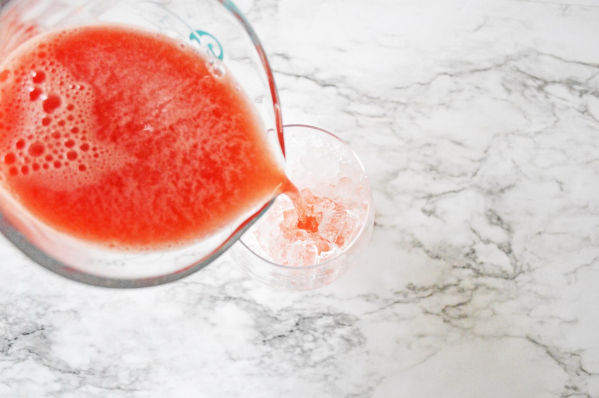 Pouring watermelon juice in ice filled glass