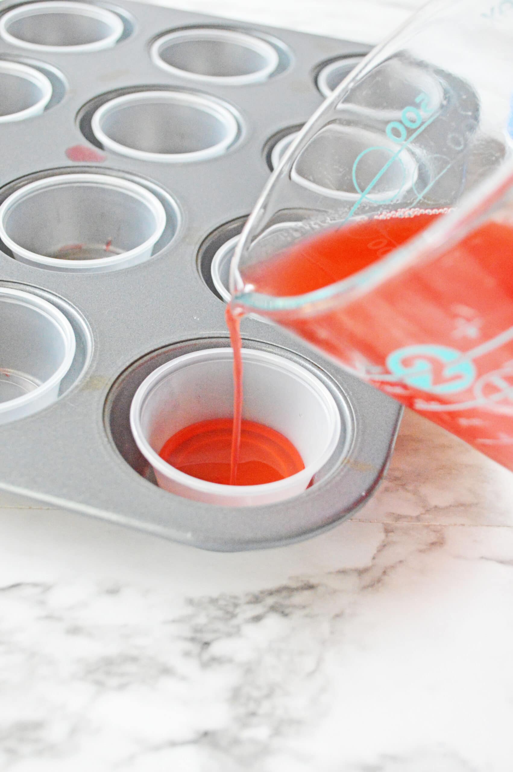 Pouring jello mixture into plastic shot cups