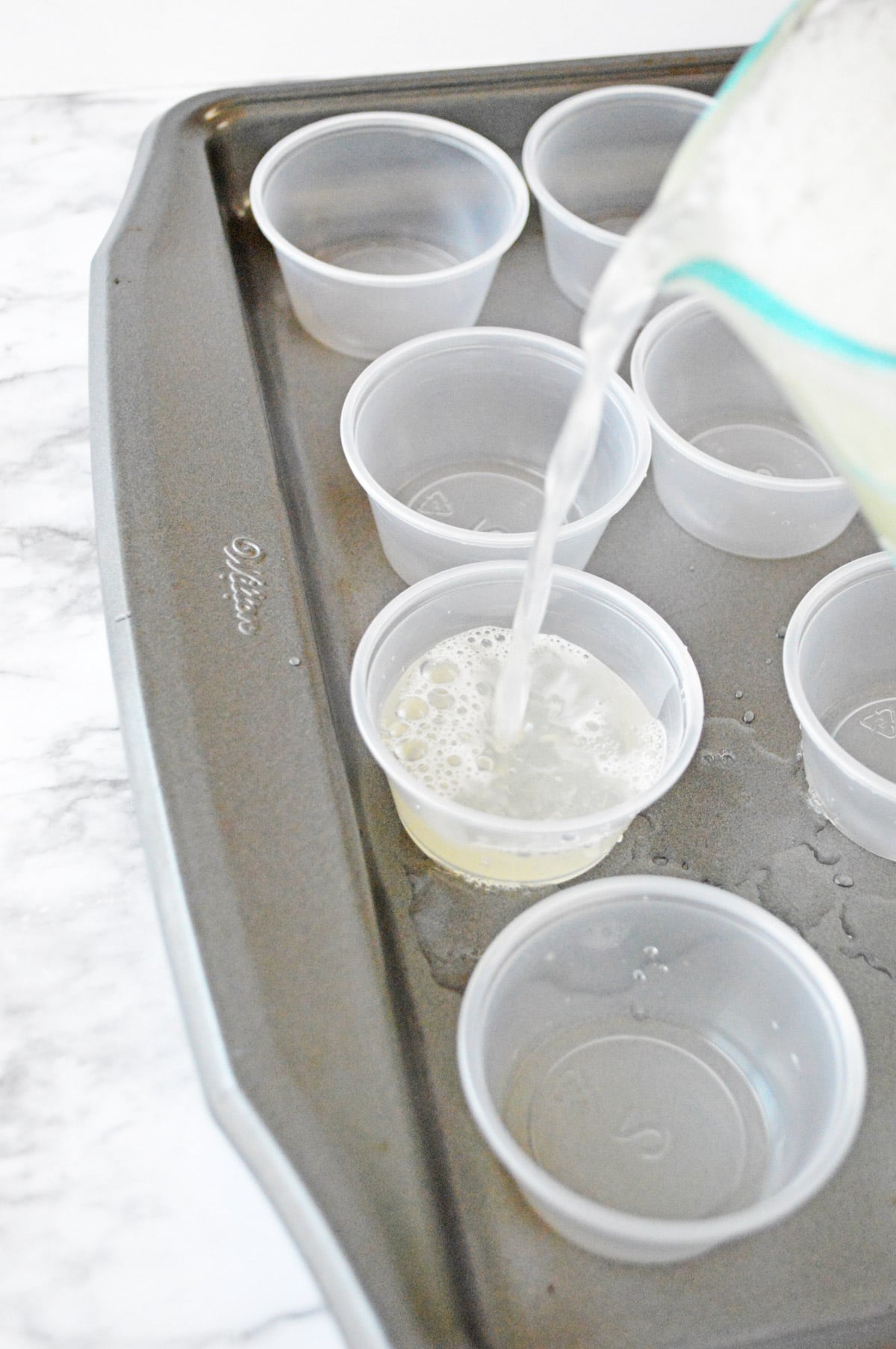 Pouring lemonade jello shots into plastic shot cups