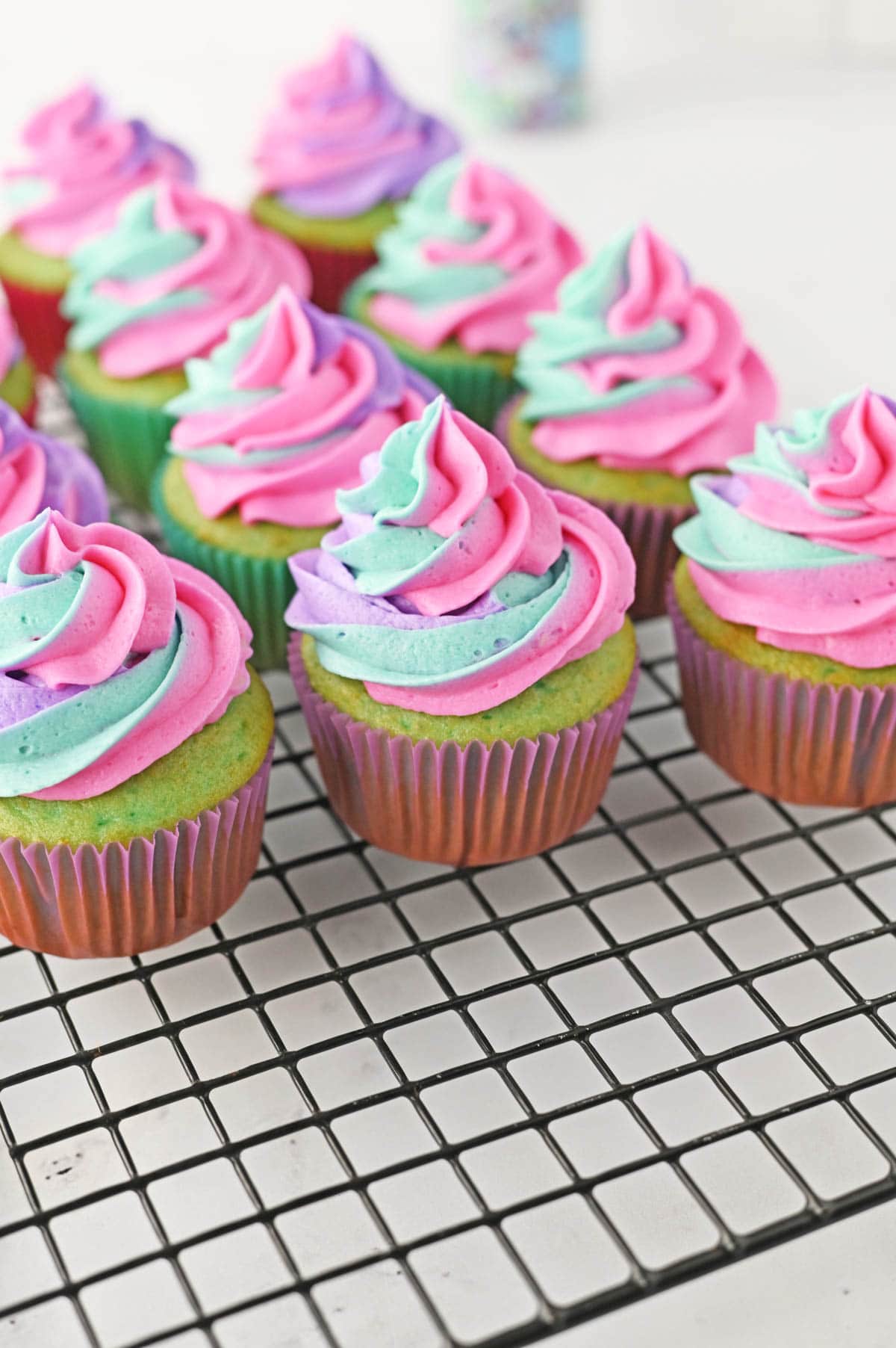 Blue-green colored cupcakes with pink, purple and teal frosting