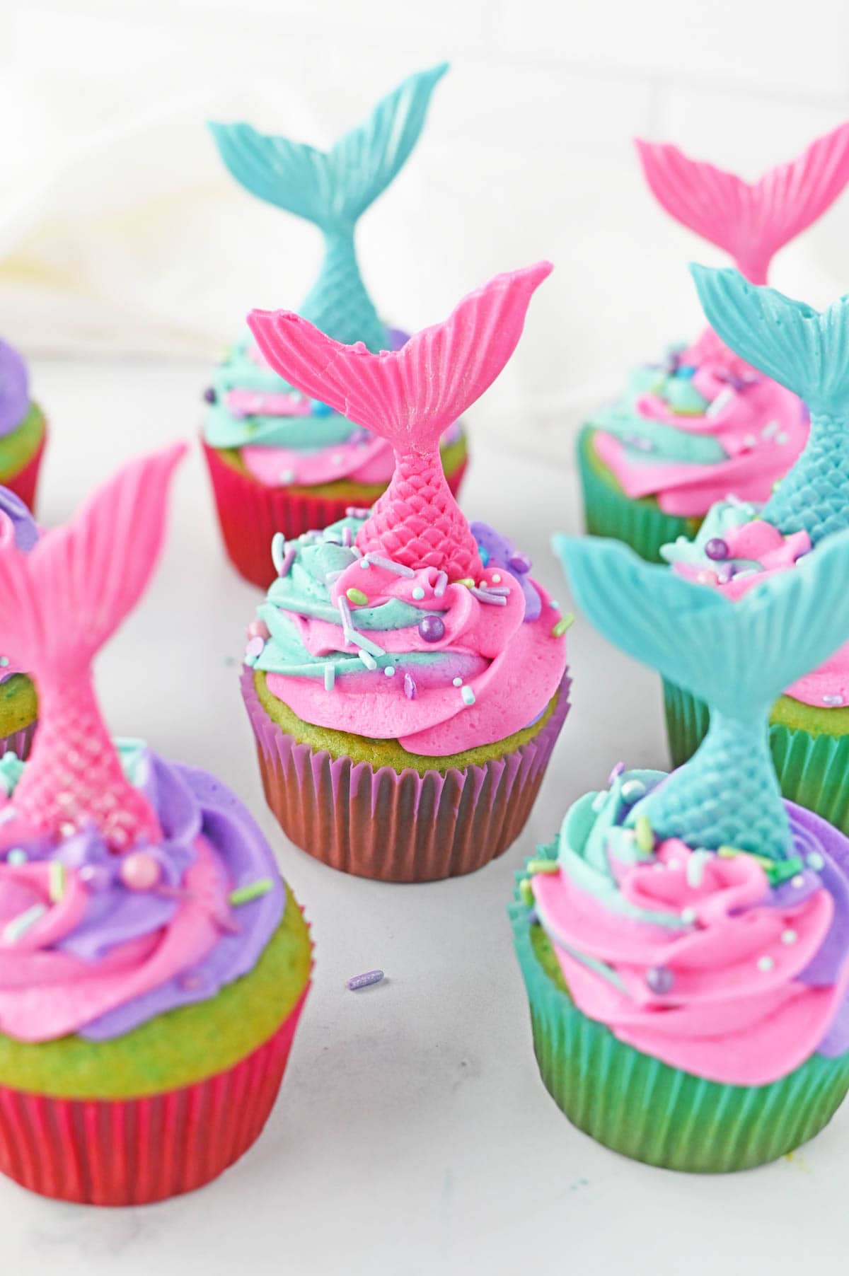 Mermaid cupcakes with pink and blue mermaid tails sticking out of the frosting