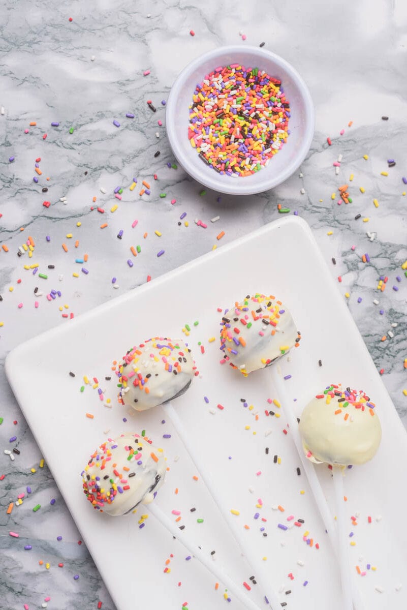Oreo cake pops with sprinkles on white plate