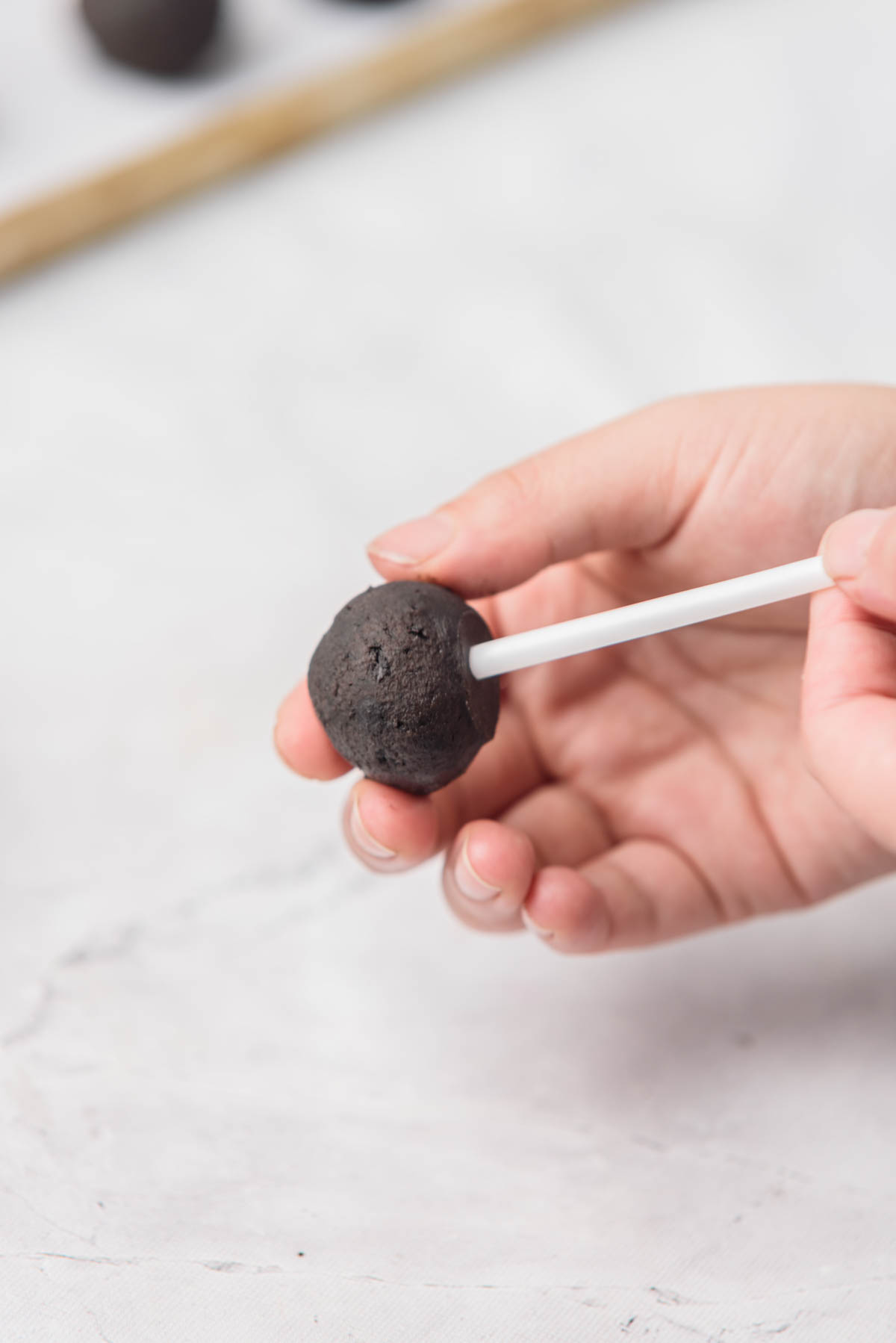 Hand placing an Oreo cookie ball onto a stick