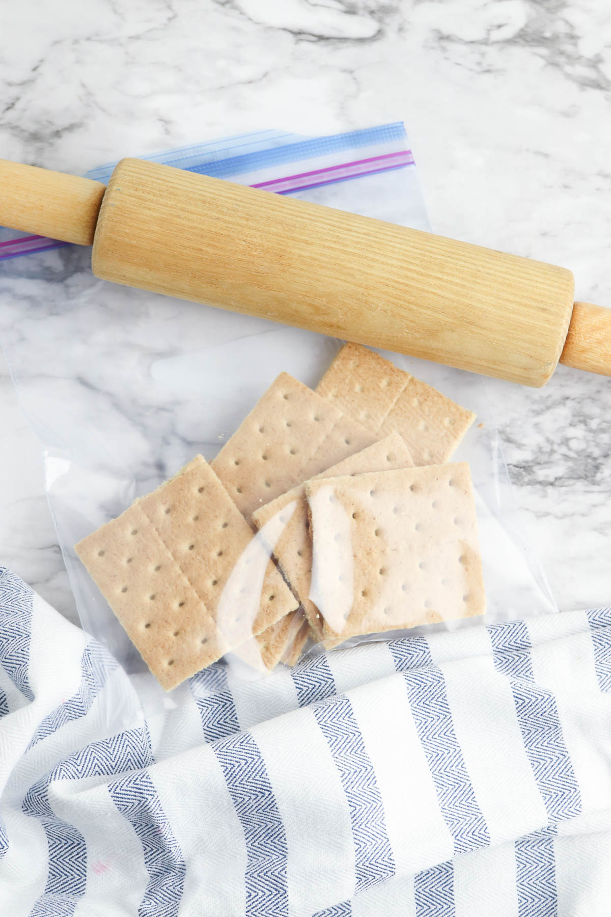 Graham crackers in plastic bag next to rolling pin