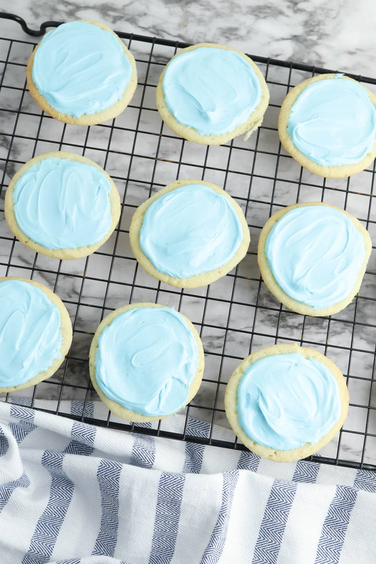 Sugar cookies with blue frosting on cooling rack