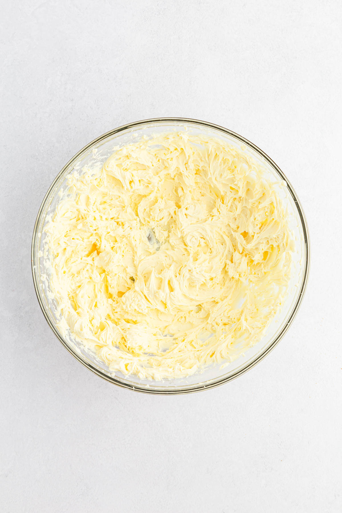 Cream cheese, powdered sugar and vanilla mixed in glass bowl