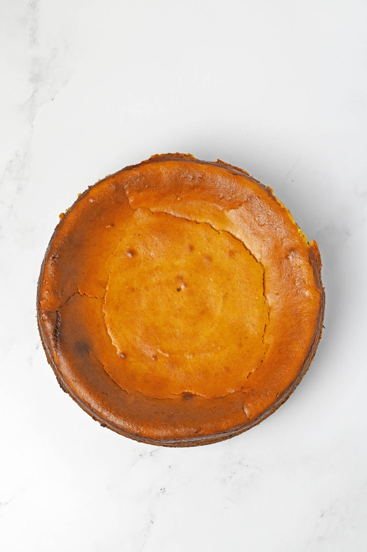 Baked pumpkin cheesecake on white marble counter