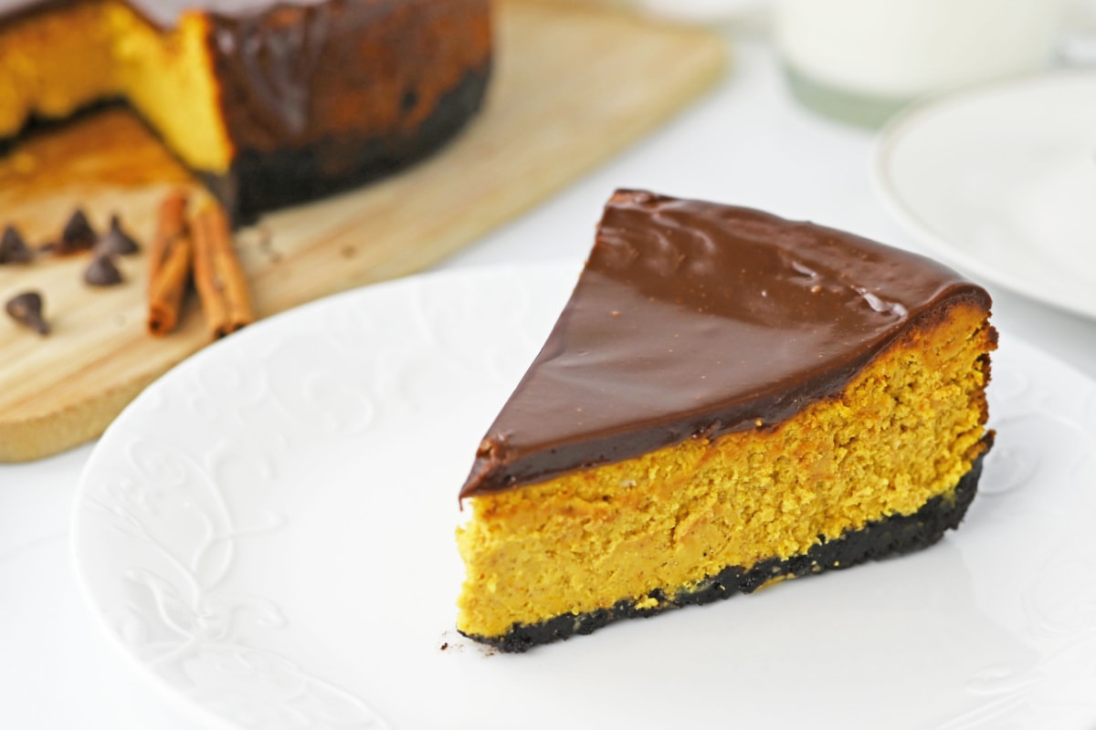 Chocolate pumpkin cheesecake on plate with large cake in background