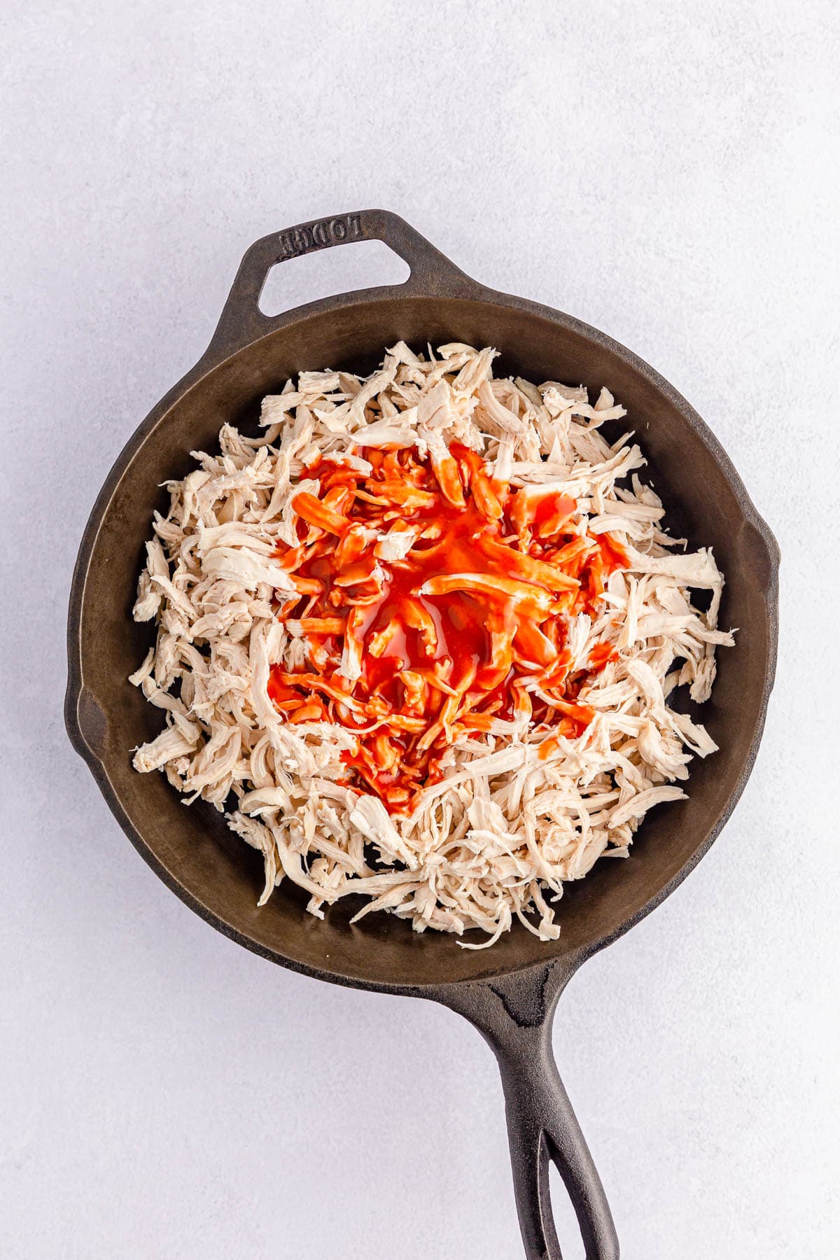 Shredded chicken and hot sauce in skillet
