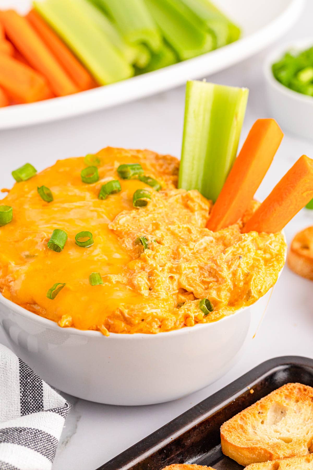 Buffalo Chicken Dip in white bowl with celery and carrot sticks