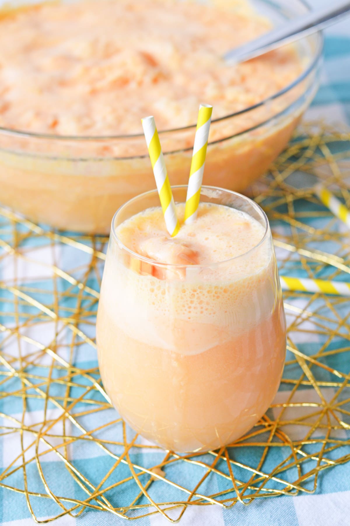 Orange punch in glass with yellow striped straws
