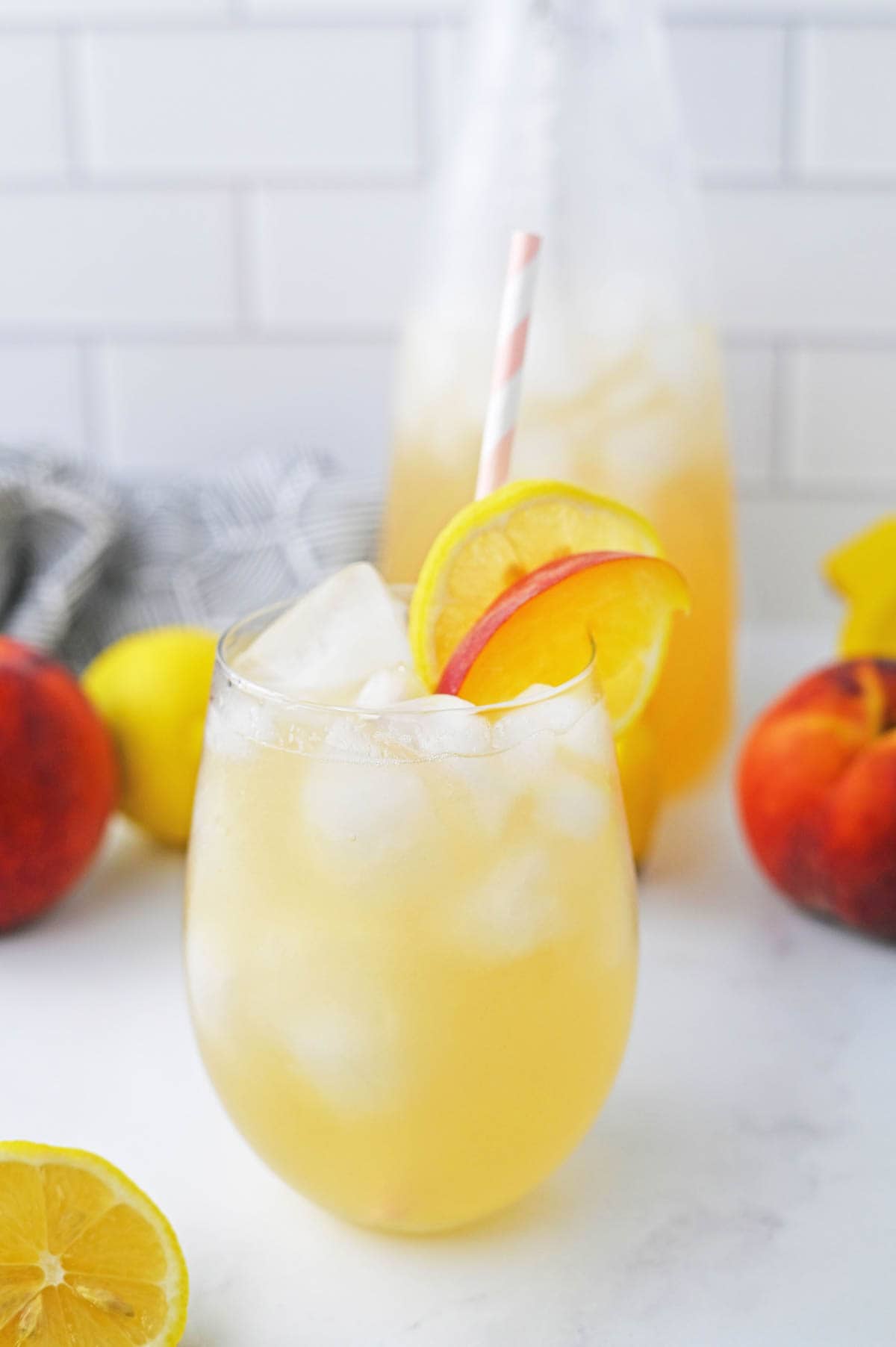 Peach lemonade in glass with lemon and peach slice