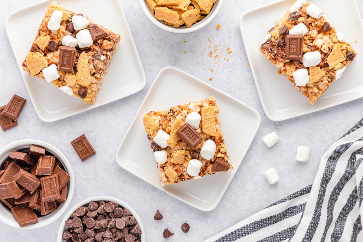 S'mores Krispie Treats on light counter surrounded by chocolate