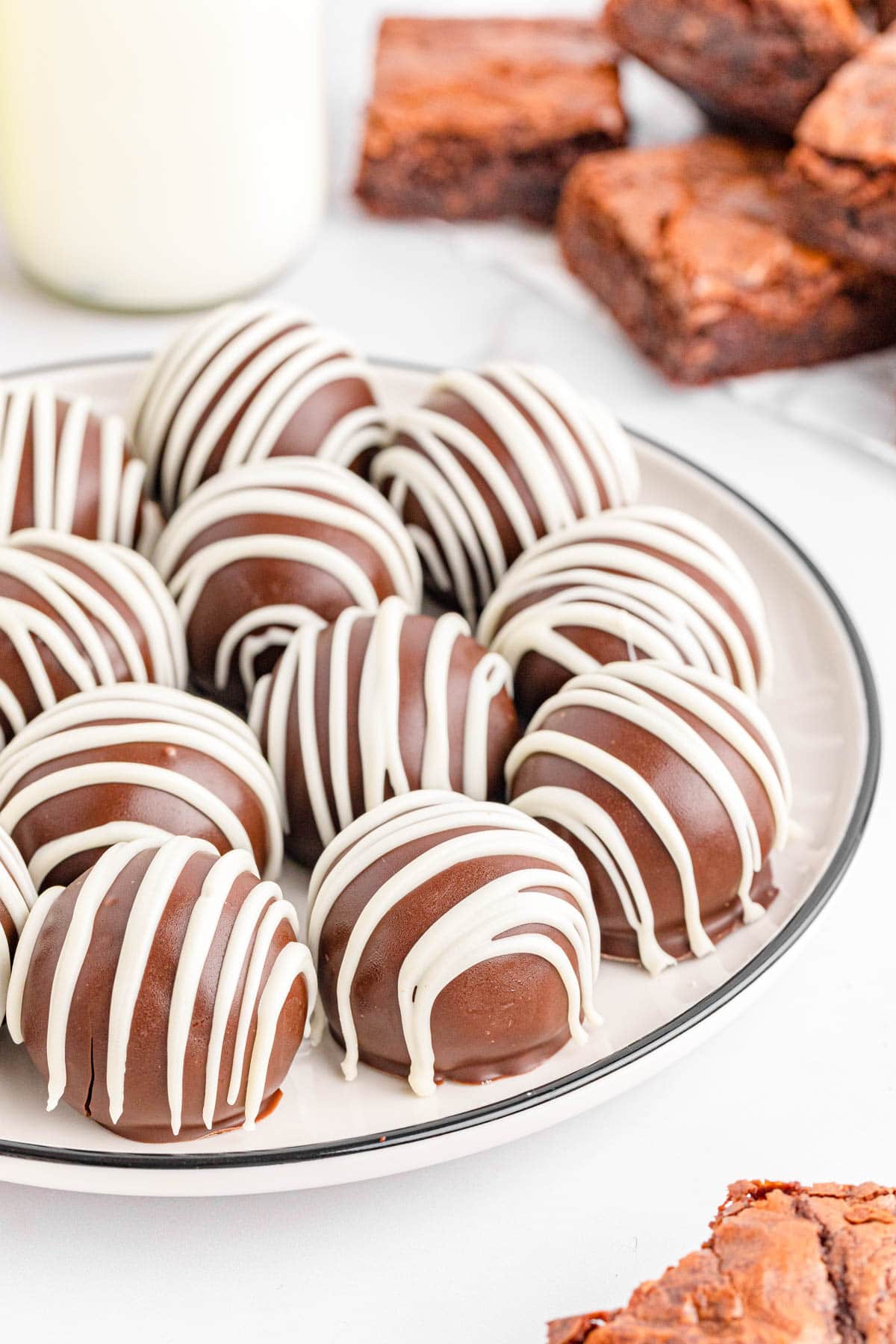 Brownie balls drizzled with white chocolate on white plate
