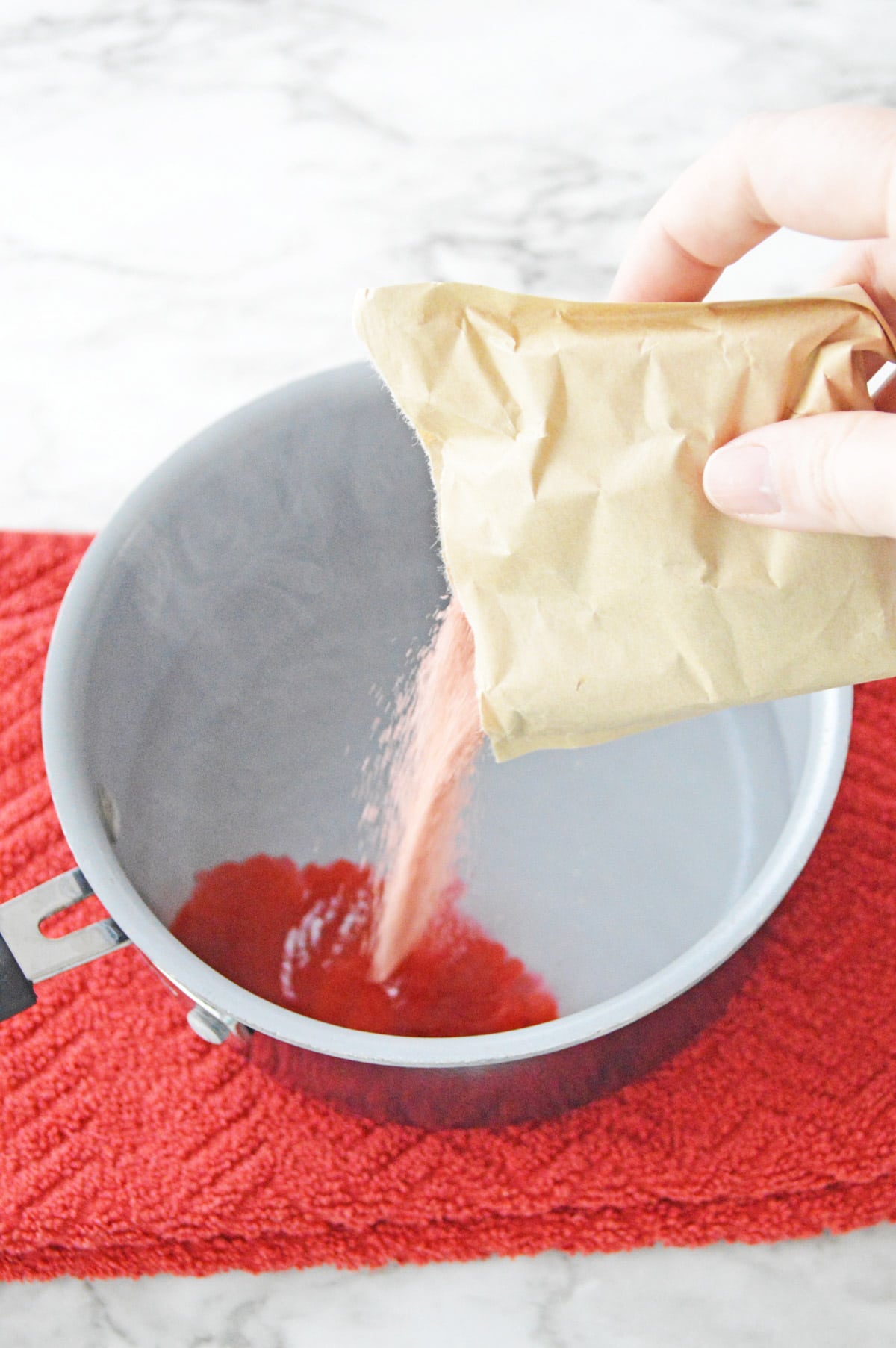 Pouring cranberry jello mix into saucepan