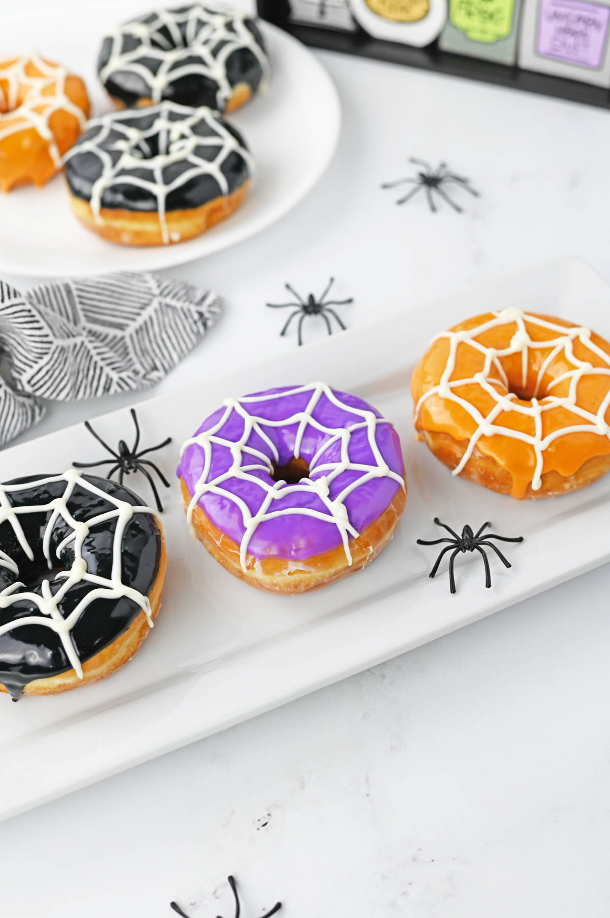 Spiderweb donuts on white plate with plastic spiders