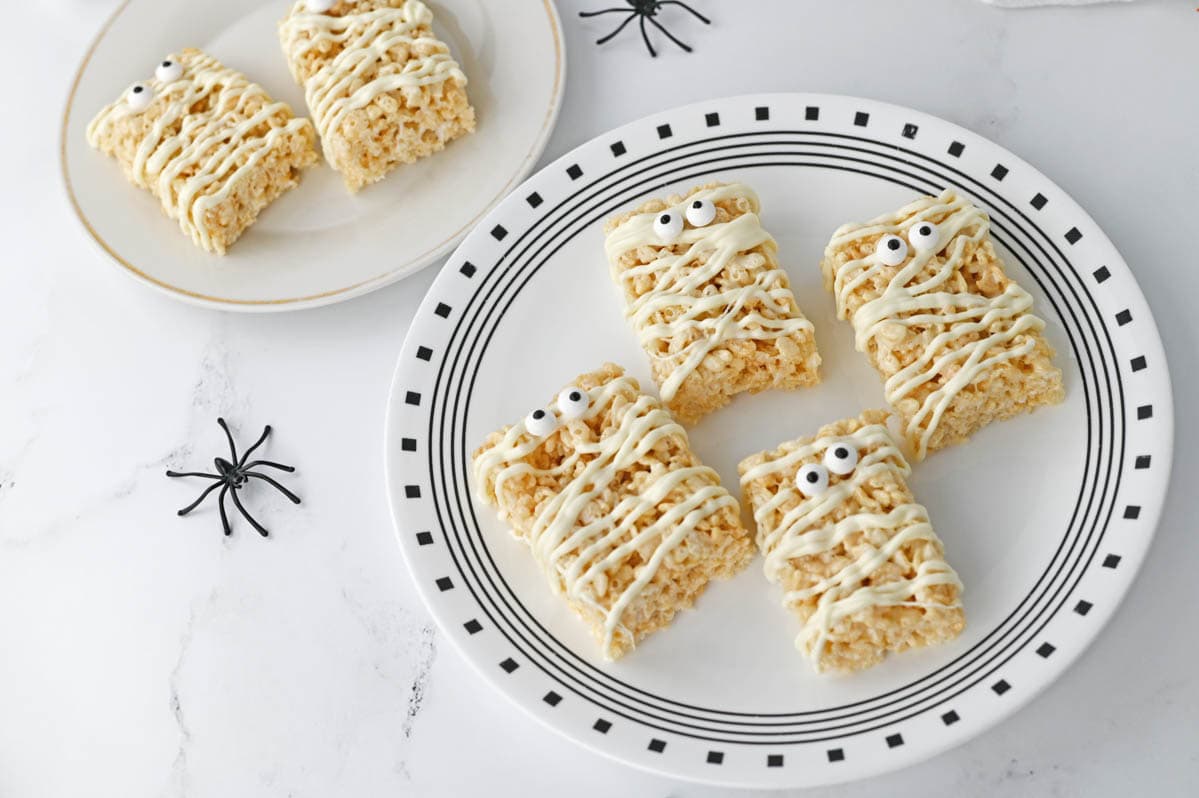 Mummy rice krispie treats on plate with plastic spiders