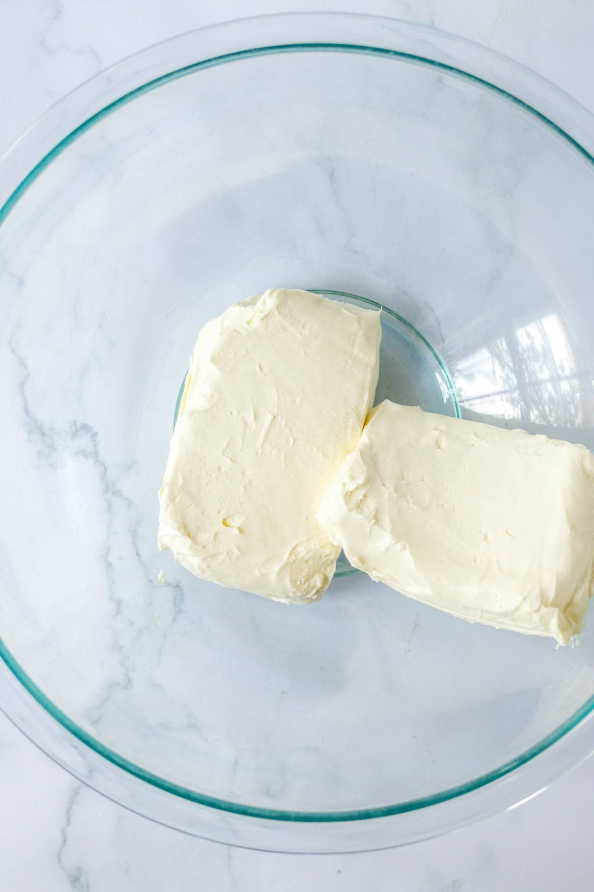 Two blocks of cream cheese in bowl