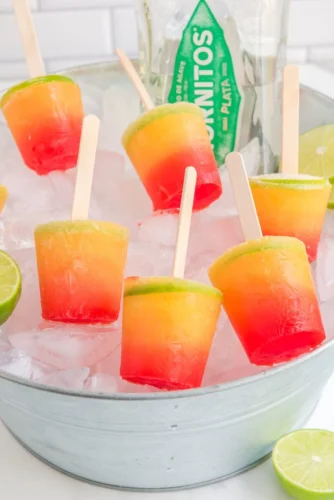 Tequila sunrise popsicles in metal tub with ice