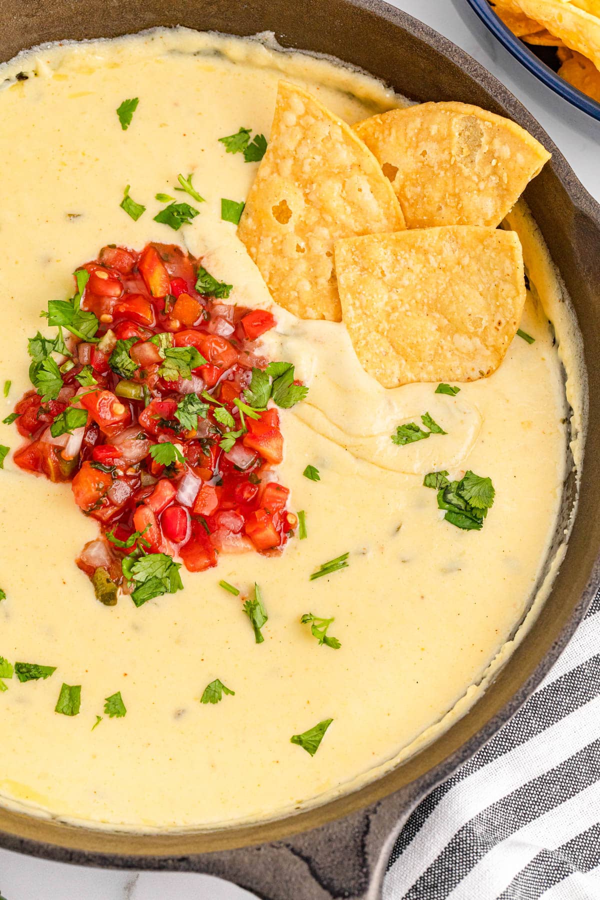 Queso dip in cast iron skillet with chips dipped in it