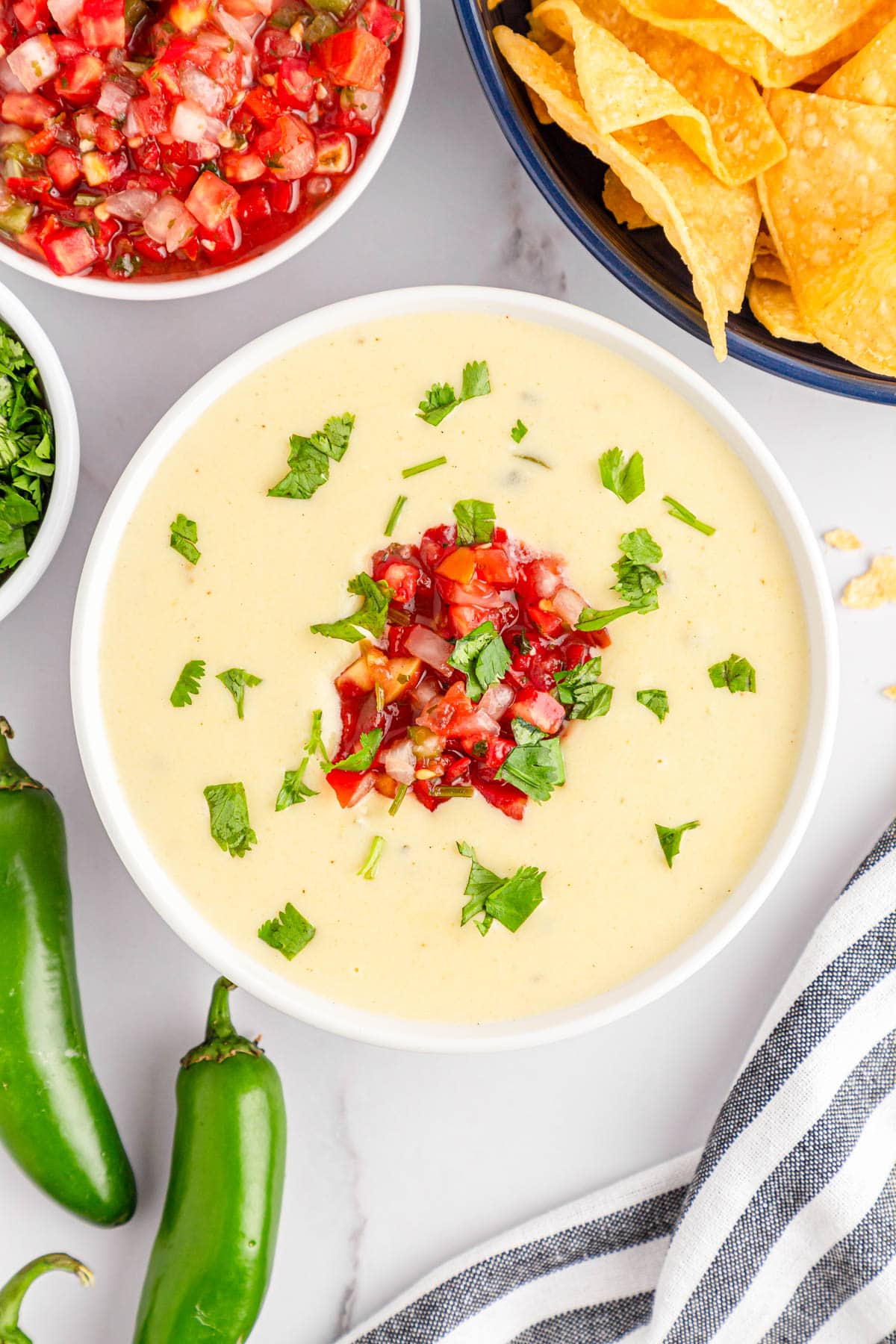 White bowl with queso dip with jalapenos and pico de gallo