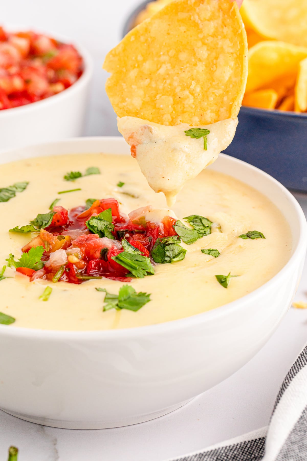 Bowl of queso with a chip dipped in it